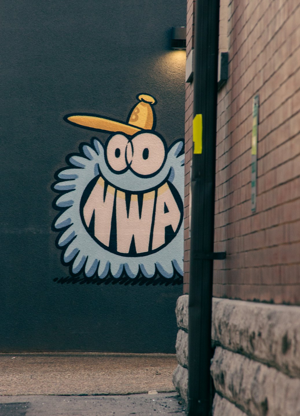 A playful cartoon monster mural with a baseball cap on a wall.