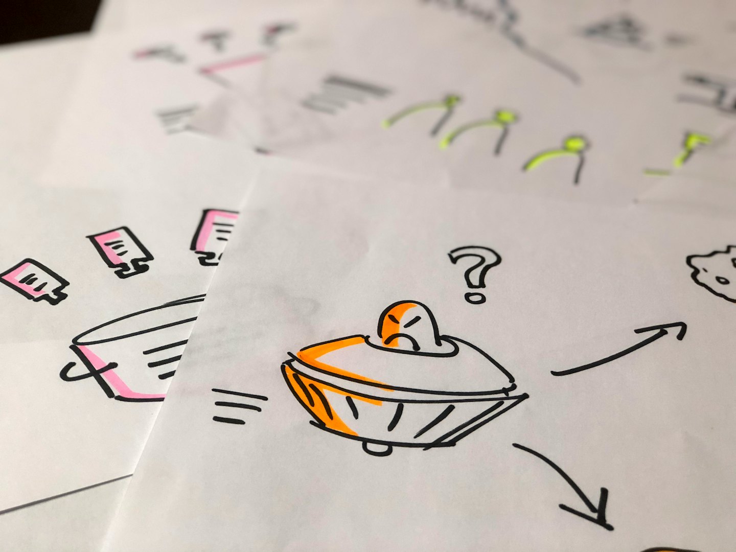 UFO doodle on scattered papers with question marks and arrows.